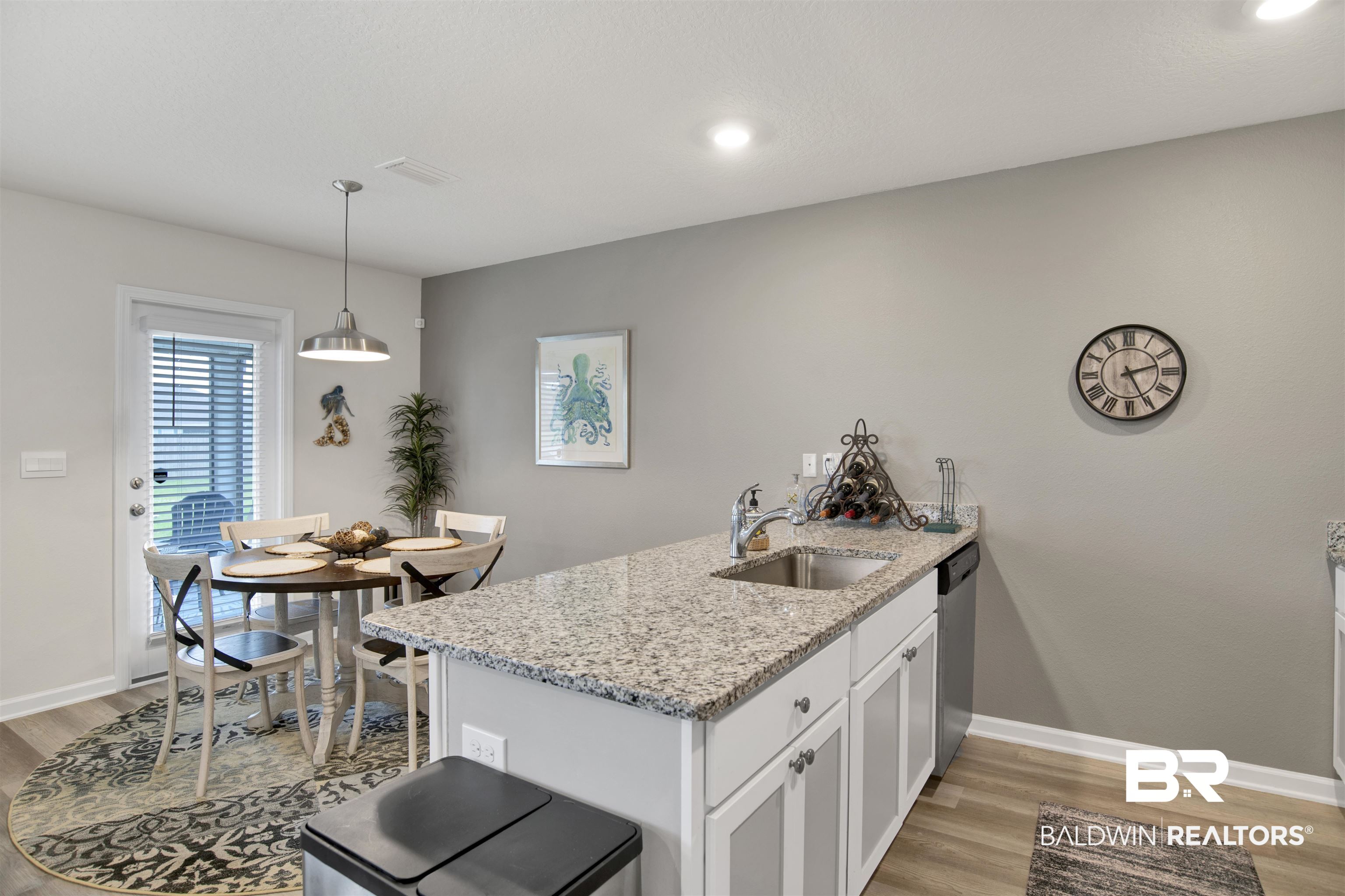 22348 Aleutian Avenue Foley, AL 36535 - Photo 11 of 32 Kitchen with a peninsula, light stone counters, light wood-style floors, hanging light fixtures, and white cabinetry