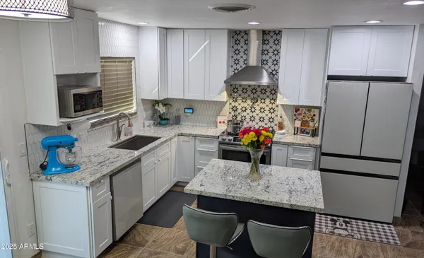 a kitchen with stainless steel appliances granite countertop a table chairs sink refrigerator and microwave