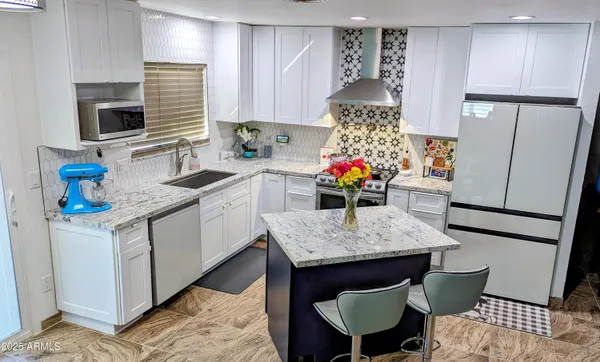 a kitchen with stainless steel appliances granite countertop a stove a refrigerator and a sink