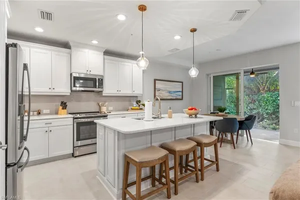 a kitchen with kitchen island granite countertop a table chairs sink and cabinets