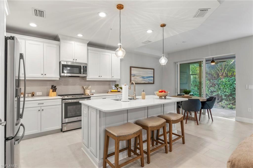 2640 Seychelles Circle, Unit 2802 Naples, FL 34112 - Photo 13 of 32 a kitchen with kitchen island granite countertop a table chairs sink and cabinets