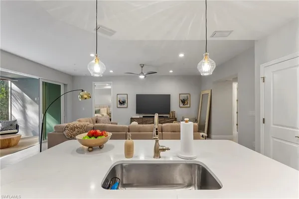 a kitchen with a sink a counter and living room view