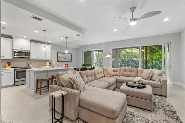 a living room with stainless steel appliances kitchen island furniture and a large window