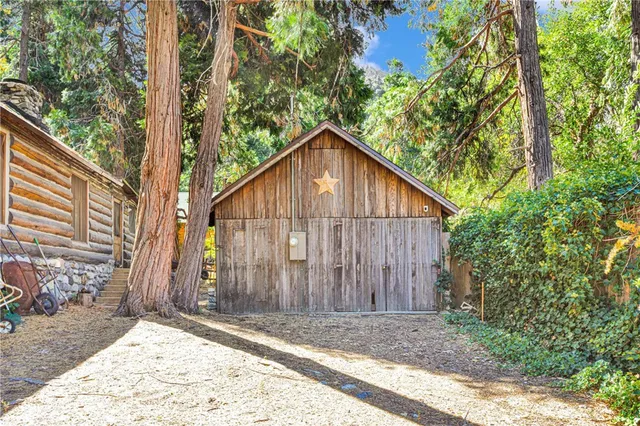 a backyard of a house with large trees and wooden fence