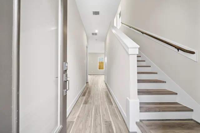 a view of a hallway with wooden floor and staircase