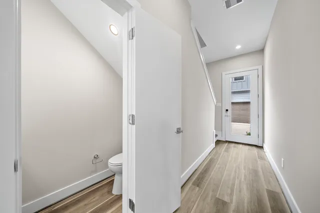 a view of a hallway view with wooden floor and a bathroom