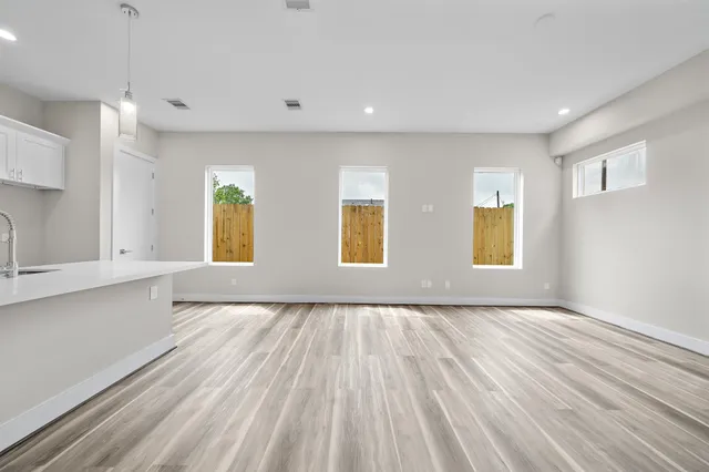 a view of an empty room with a window and wooden floor