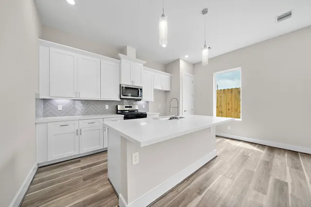 a kitchen with kitchen island a sink white cabinets and white appliances