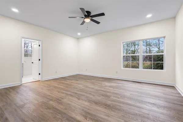 an empty room with wooden floor and ceiling fan