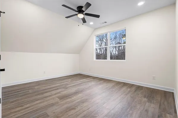 an empty room with wooden floor and ceiling fan