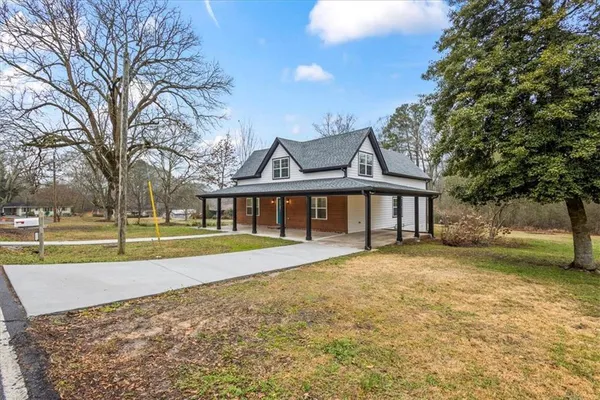 a view of a house with a yard and large trees
