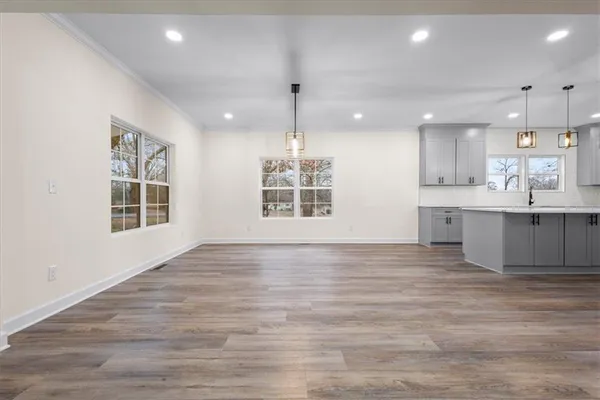 an empty room with wooden floor ceiling fan and windows
