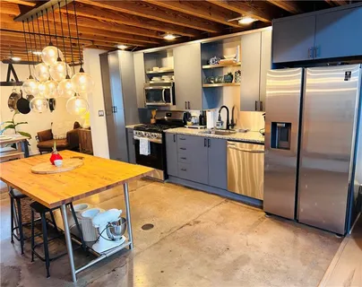 a kitchen with stainless steel appliances kitchen island granite countertop a table chairs and a refrigerator