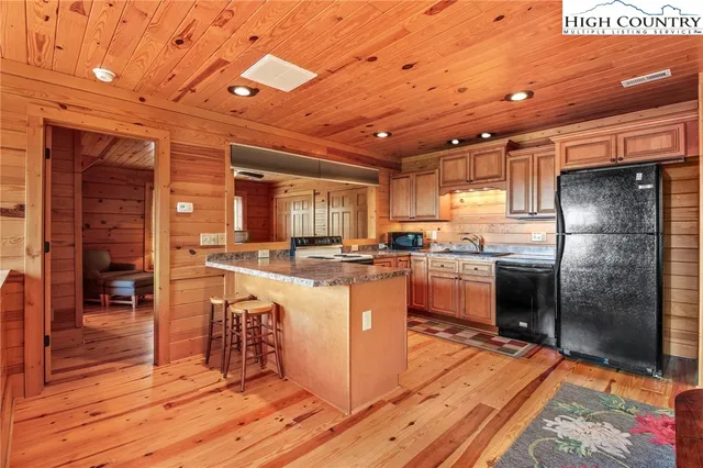 a living room with stainless steel appliances granite countertop furniture and a wooden floor