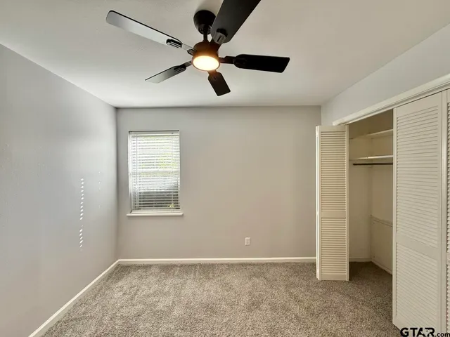 an empty room with a window and a ceiling fan