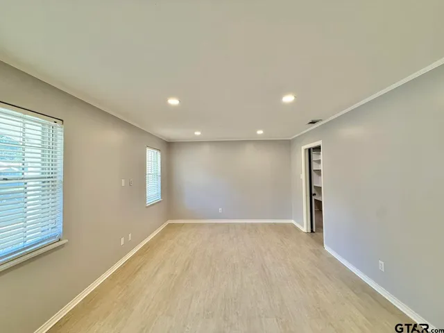 an empty room with wooden floor and windows