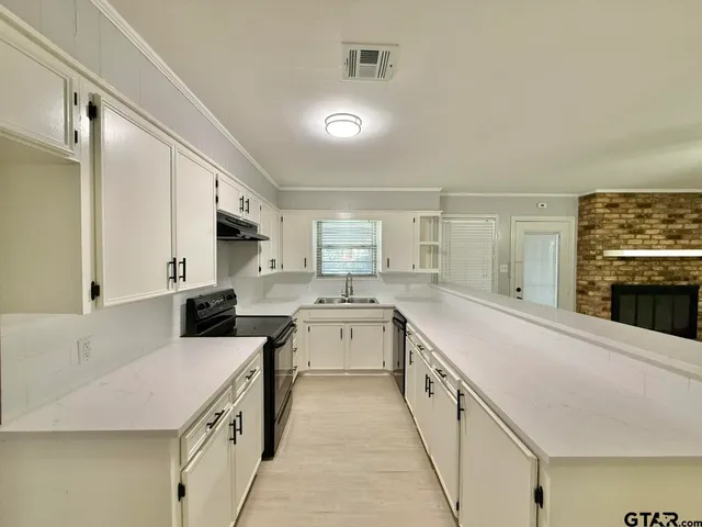 a large white kitchen with stainless steel appliances granite countertop a stove and a sink