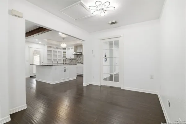 an empty room with wooden floor and kitchen view