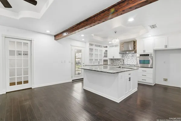 a kitchen with granite countertop white cabinets and wooden floors