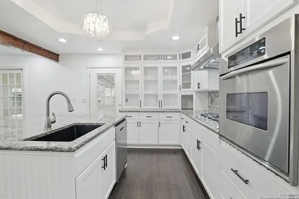 a large white kitchen with stainless steel appliances granite countertop a sink and cabinets