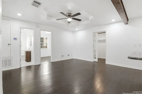a view of an empty room with wooden floor and a ceiling fan