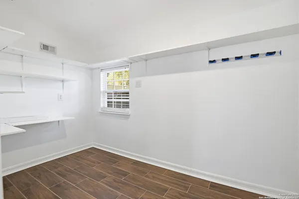 a view of an empty room with wooden floor and a window