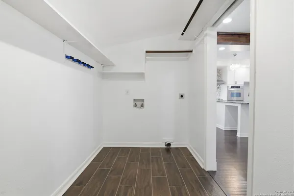 a view of a hallway with wooden floor and a bathroom