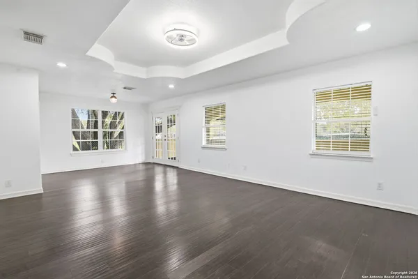 an empty room with wooden floor and windows
