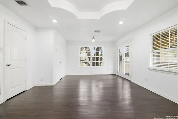 an empty room with wooden floor and windows