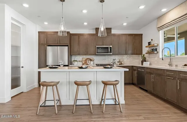 a kitchen with stainless steel appliances granite countertop a kitchen island hardwood floor sink and stove