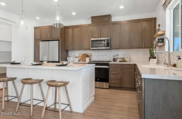 a kitchen with stainless steel appliances granite countertop a sink a stove a refrigerator and island with wooden floor