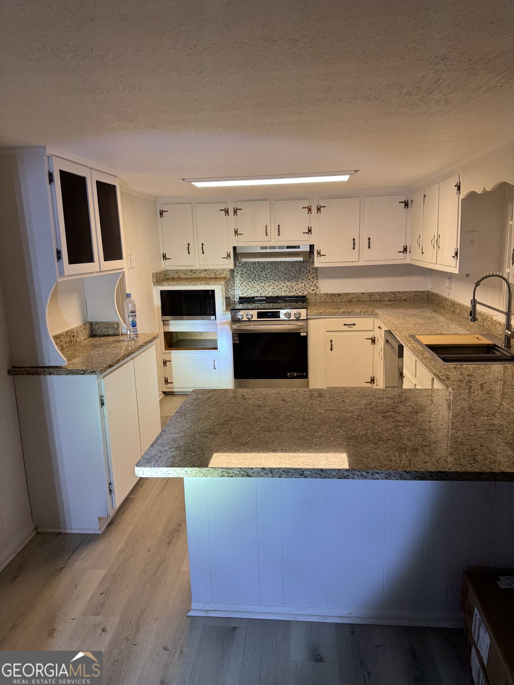 2363 Alvin Joiner Road Dublin, GA 31021 - Photo 33 of 35 a kitchen with stainless steel appliances granite countertop a sink a stove top oven a chimney and a center island