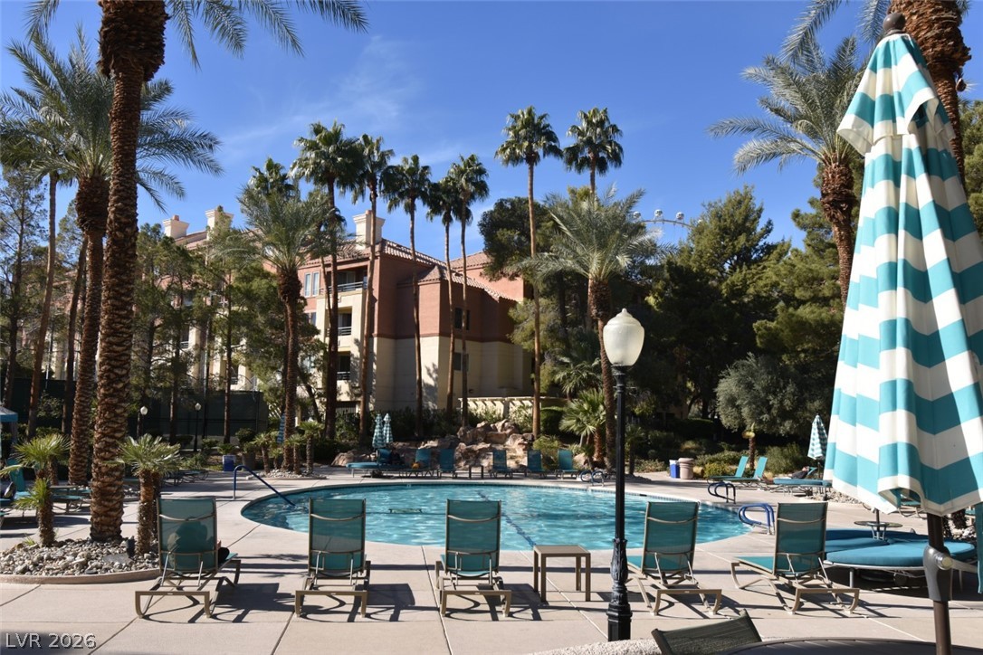210 East Flamingo Road, Unit 137 Las Vegas, NV 89169 - Photo 2 of 32 A tranquil oasis awaits, complete with a sparkling pool and inviting lounge areas under swaying palm trees.