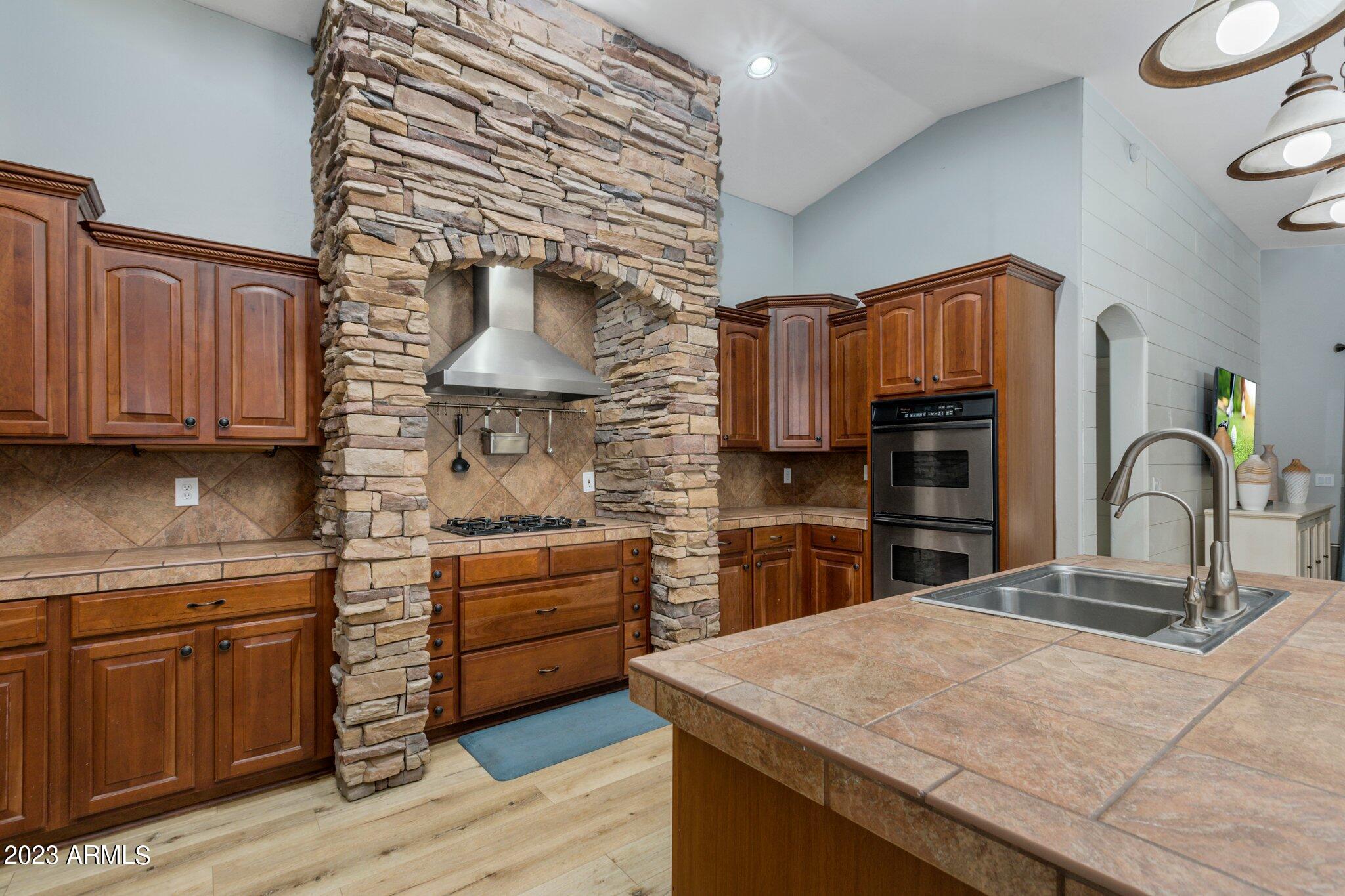 4565 East Ruffian Road Gilbert, AZ 85297 - Photo 10 of 47 a kitchen with stainless steel appliances kitchen island granite countertop a stove a sink dishwasher and a wooden cabinets