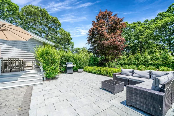 a view of a patio with couches and a potted plant on a brick wall