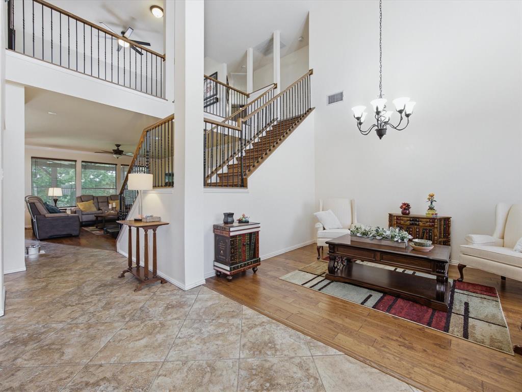 4008 Falcon Ridge Drive Haltom City, TX 76137 - Photo 6 of 40 Two-story foyer featuring high ceilings, a wrought iron chandelier, wood-finish flooring, and a staircase with an open railing