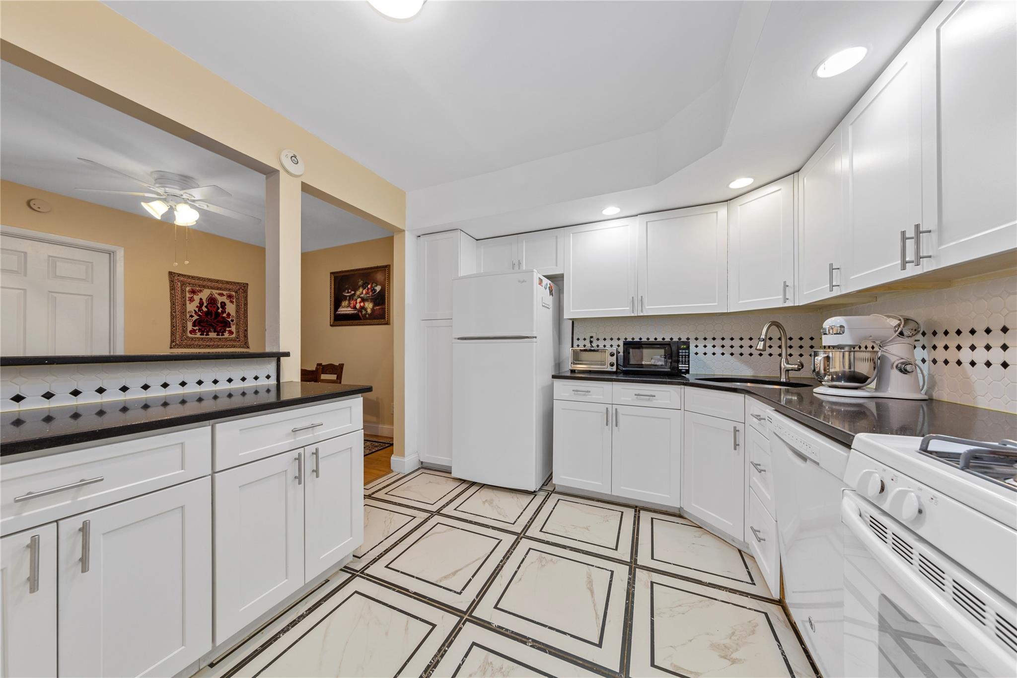 71-09 Sutton Place, Unit 2 Queens, NY 11365 - Photo 13 of 20 Kitchen with a sink, dark countertops, white cabinets, and white appliances
