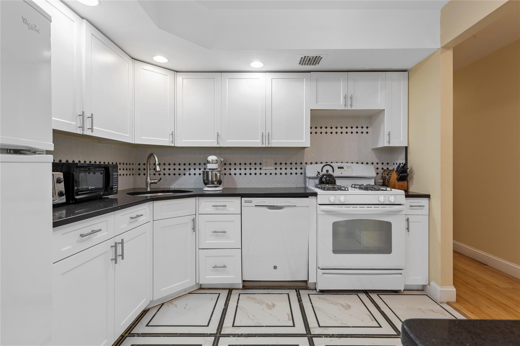 71-09 Sutton Place, Unit 2 Queens, NY 11365 - Photo 14 of 20 Kitchen featuring a sink, dark countertops, white appliances, and visible vents