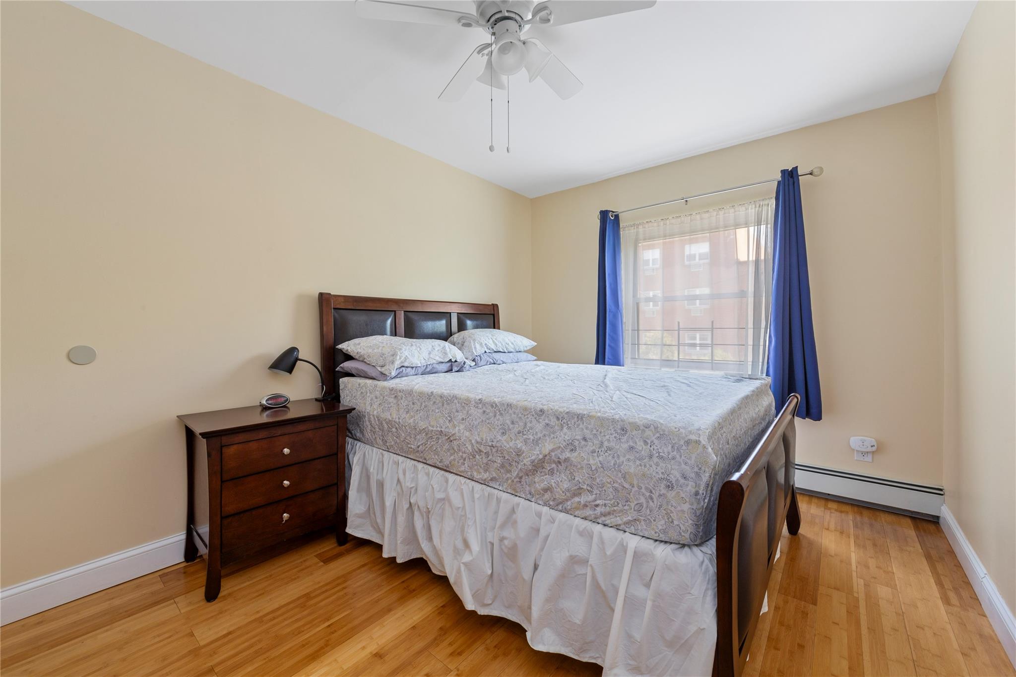 71-09 Sutton Place, Unit 2 Queens, NY 11365 - Photo 5 of 20 Bedroom featuring light wood-style floors, baseboards, baseboard heating, and a ceiling fan