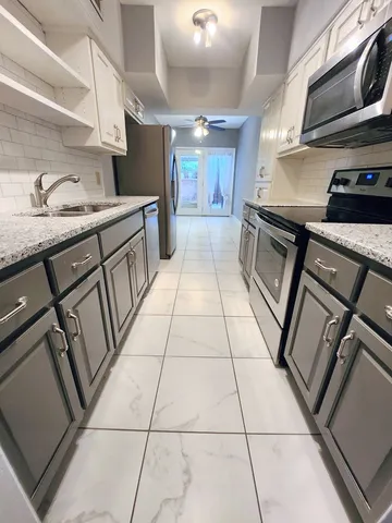 a kitchen with granite countertop a sink a stove and cabinets