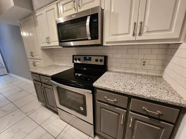 a kitchen with granite countertop white cabinets stainless steel appliances and a sink
