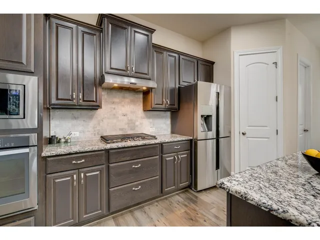a kitchen with stainless steel appliances granite countertop a refrigerator and a stove