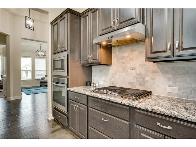 a kitchen with granite countertop a sink cabinets and stainless steel appliances