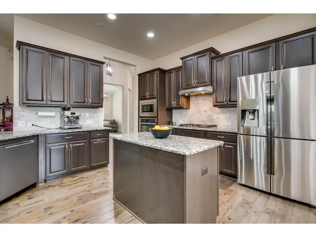 a kitchen with granite countertop a refrigerator stove top oven and cabinets