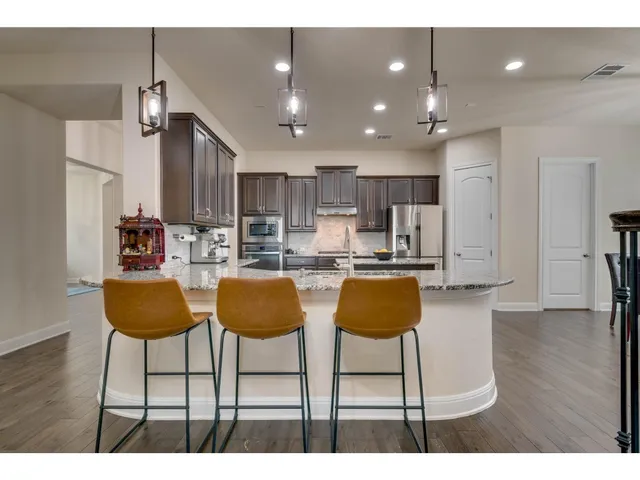 a kitchen with granite countertop a counter space chairs stainless steel appliances and cabinets