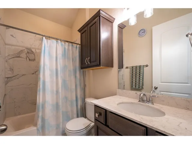 a bathroom with a granite countertop sink a mirror and a shower