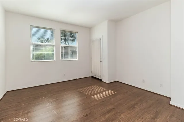 an empty room with wooden floor & windows