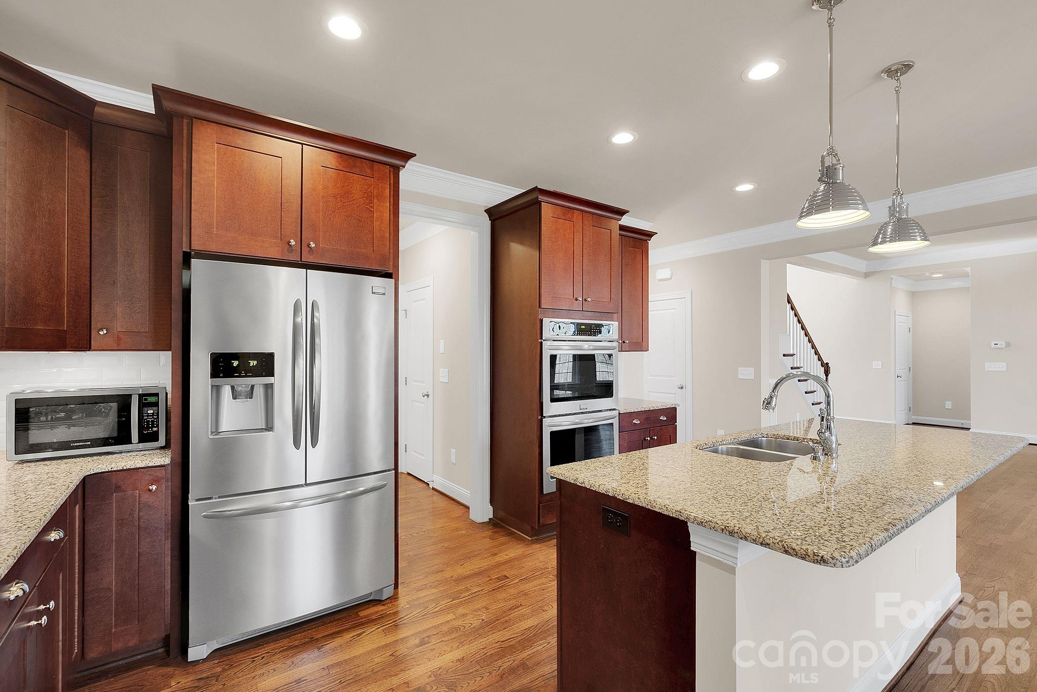 535 Brightleaf Place Northwest Concord, NC 28027 - Photo 12 of 48 a kitchen with stainless steel appliances granite countertop a refrigerator a sink dishwasher a stove and a refrigerator with wooden floor