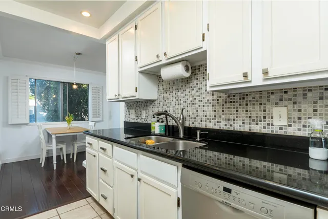 a kitchen with stainless steel appliances granite countertop a sink a stove and white cabinets