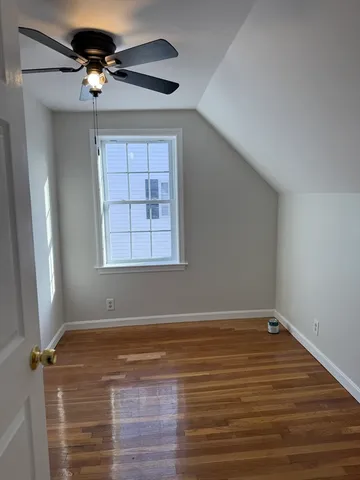 a view of empty room with wooden floor and fan